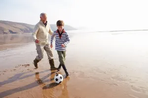 Two people kicking a soccer ball on the beach